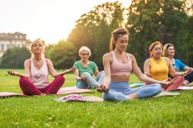 Parkta fitness eğitmeniyle eğitim gören çok ırklı yaşlı kadınlar grubu - aktif yaşlılar spor yapıyor.