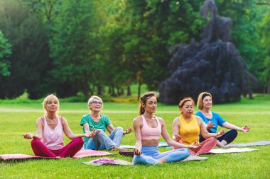 Parkta fitness eğitmeniyle eğitim gören çok ırklı yaşlı kadınlar grubu - aktif yaşlılar spor yapıyor.