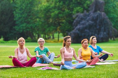 Parkta fitness eğitmeniyle eğitim gören çok ırklı yaşlı kadınlar grubu - aktif yaşlılar spor yapıyor.