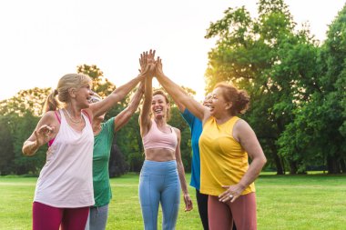 Parkta fitness eğitmeniyle eğitim gören çok ırklı yaşlı kadınlar grubu - aktif yaşlılar spor yapıyor.