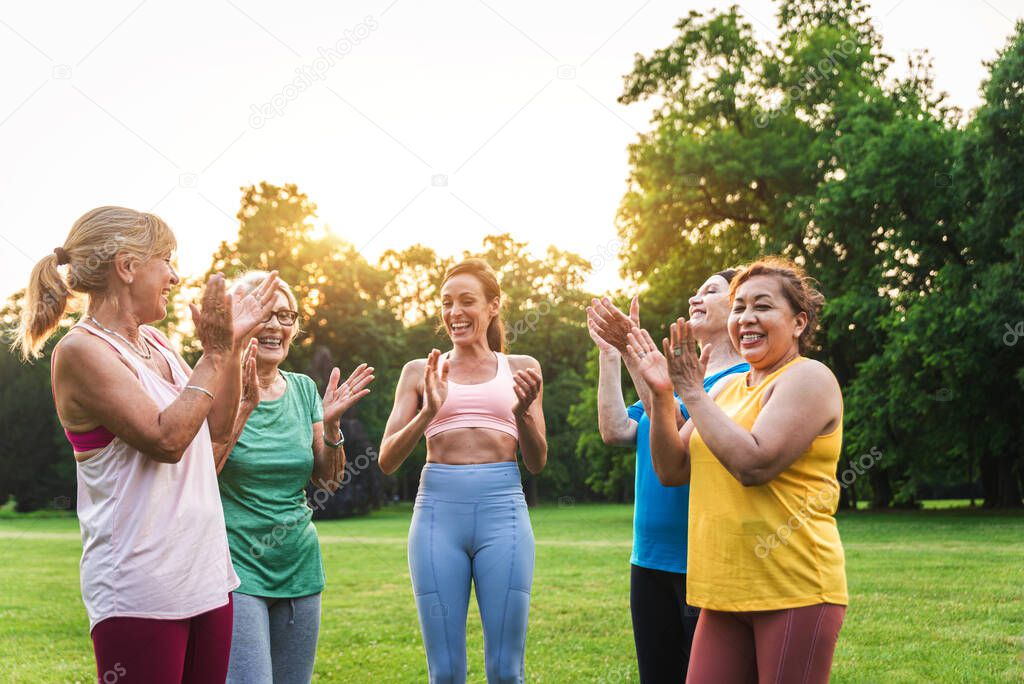 Multiethnic group of senior women training at park with fitness instructor - Active elderly people doing sport in the nature