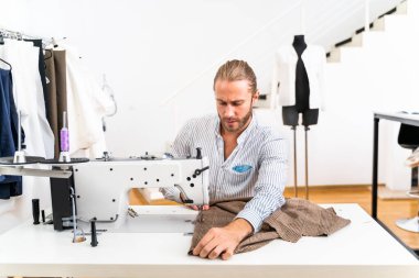 Elbise tasarımcısı, tekstil fabrikasında bir giyim markası üzerinde çalışan moda tasarımcısı için yeni bir tasarım yapıyor.