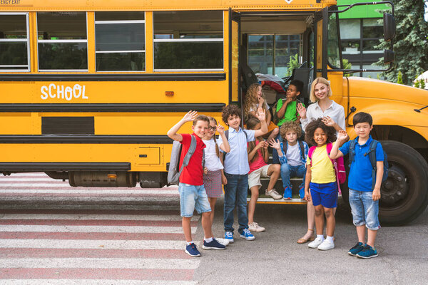 Group of young students attending primary school on a yellow school bus - Elementary school kids ha1ving fun