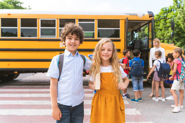 Group of young students attending primary school on a yellow school bus - Elementary school kids ha1ving fun