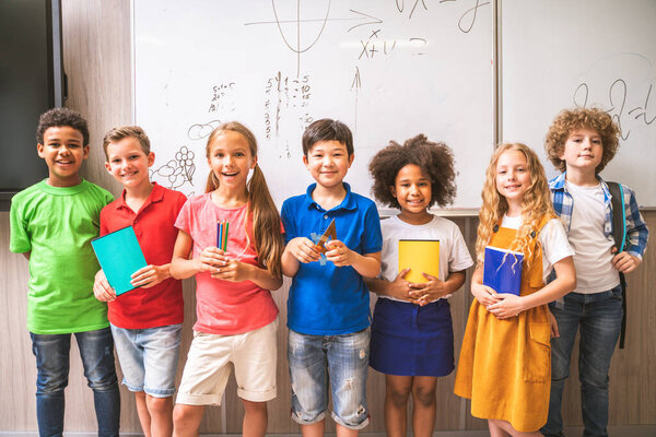 Multiracial group of kids at primary school - Playful schoolers enjoying school time and lesson with teacher and classmates