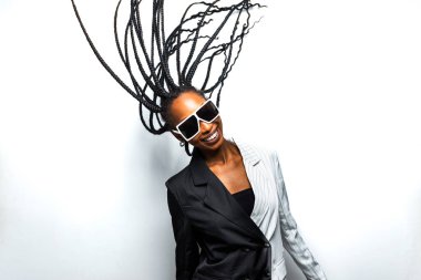 Güzel afro-amerikan kadın saçını örüyor ve şık kıyafetler giyiyor - Stüdyoda genç siyah bir kızın portresi