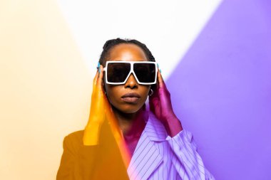 Güzel afro-amerikan kadın saçını örüyor ve şık kıyafetler giyiyor - Stüdyoda genç siyah bir kızın portresi