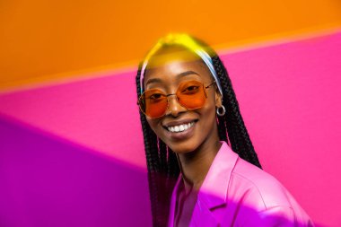 Güzel afro-amerikan kadın saçını örüyor ve şık kıyafetler giyiyor - Stüdyoda genç siyah bir kızın portresi