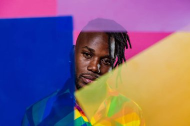 Jel lambalı sanatsal portre. Renkli arka planlarda poz veren yakışıklı bir adam.