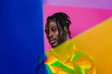 Jel lambalı sanatsal portre. Renkli arka planlarda poz veren yakışıklı bir adam.