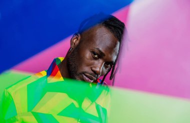 Jel lambalı sanatsal portre. Renkli arka planlarda poz veren yakışıklı bir adam.