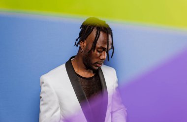 Jel lambalı sanatsal portre. Renkli arka planlarda poz veren yakışıklı bir adam.