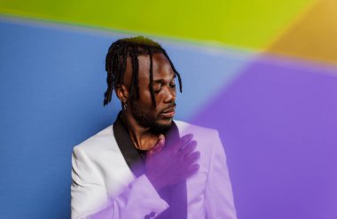 Jel lambalı sanatsal portre. Renkli arka planlarda poz veren yakışıklı bir adam.