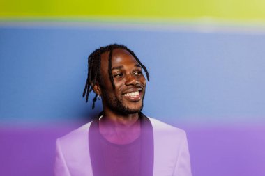 Jel lambalı sanatsal portre. Renkli arka planlarda poz veren yakışıklı bir adam.