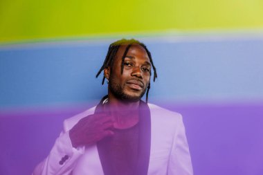 Jel lambalı sanatsal portre. Renkli arka planlarda poz veren yakışıklı bir adam.