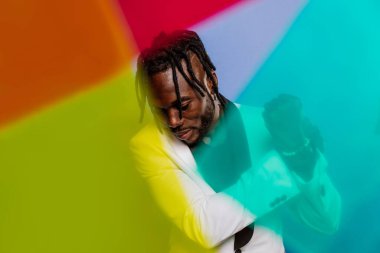 Jel lambalı sanatsal portre. Renkli arka planlarda poz veren yakışıklı bir adam.