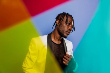 Jel lambalı sanatsal portre. Renkli arka planlarda poz veren yakışıklı bir adam.