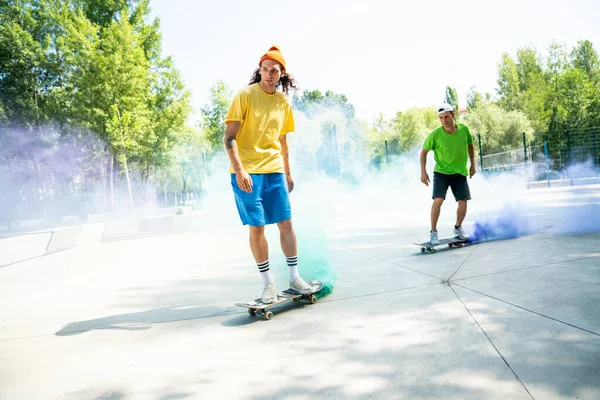 色の煙爆弾を持つスケーター スケートパークで楽しんでいるプロのスケートボーダー — ストック写真