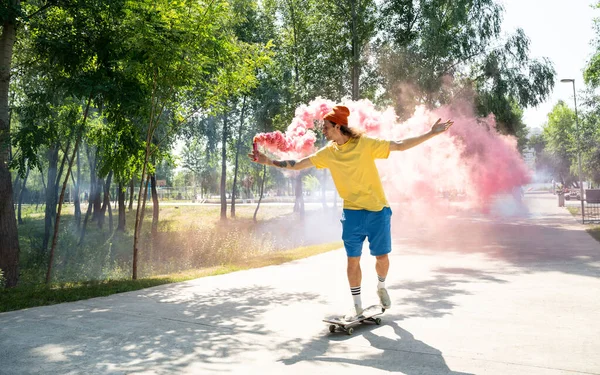 Skaters with colored smoke bombs. Professional skateboarders having fun at the skate park