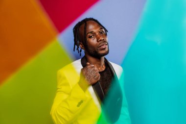 Jel lambalı sanatsal portre. Renkli arka planlarda poz veren yakışıklı bir adam.