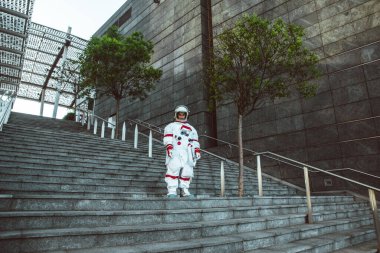 Fütürist bir istasyonda uzay adamı. Uzay giysili bir adam şehir bölgesinde yürüyor.