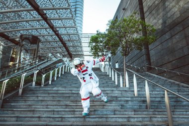 Fütürist bir istasyonda uzay adamı. Uzay giysili bir adam şehir bölgesinde yürüyor.