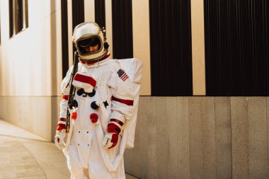 Fütürist bir istasyonda uzay adamı. Uzay giysili bir adam şehir bölgesinde yürüyor.