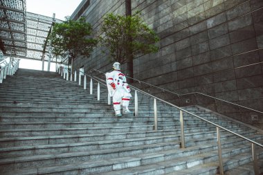 Fütürist bir istasyonda uzay adamı. Uzay giysili bir adam şehir bölgesinde yürüyor.