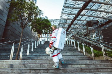 Fütürist bir istasyonda uzay adamı. Uzay giysili bir adam şehir bölgesinde yürüyor.