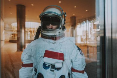 Fütürist bir istasyonda uzay adamı. Uzay giysili bir adam şehir bölgesinde yürüyor.