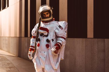 Fütürist bir istasyonda uzay adamı. Uzay giysili bir adam şehir bölgesinde yürüyor.