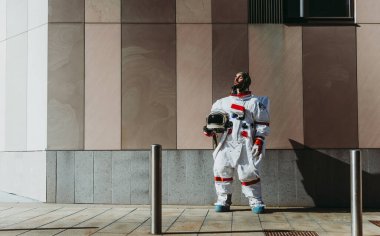 Fütürist bir istasyonda uzay adamı. Uzay giysili astronot kentsel alanda yürüyor.