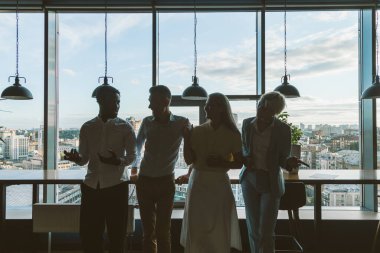 Çok ırklı bir iş ekibinin sinematik görüntüsü. Çalışanlar tatilde balkonda birlikte konuşuyorlar.