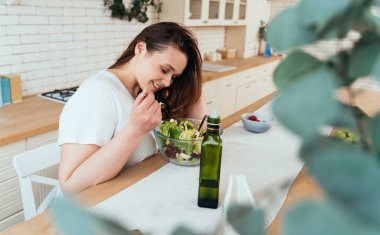 Evdeki genç bir kadının yaşam tarzı. Kadın mutfakta salata hazırlıyor.