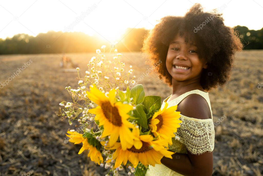 Pretty afro american girl in a sunflowers field having fun