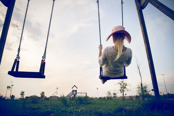 Woman playing on a swing at sunset