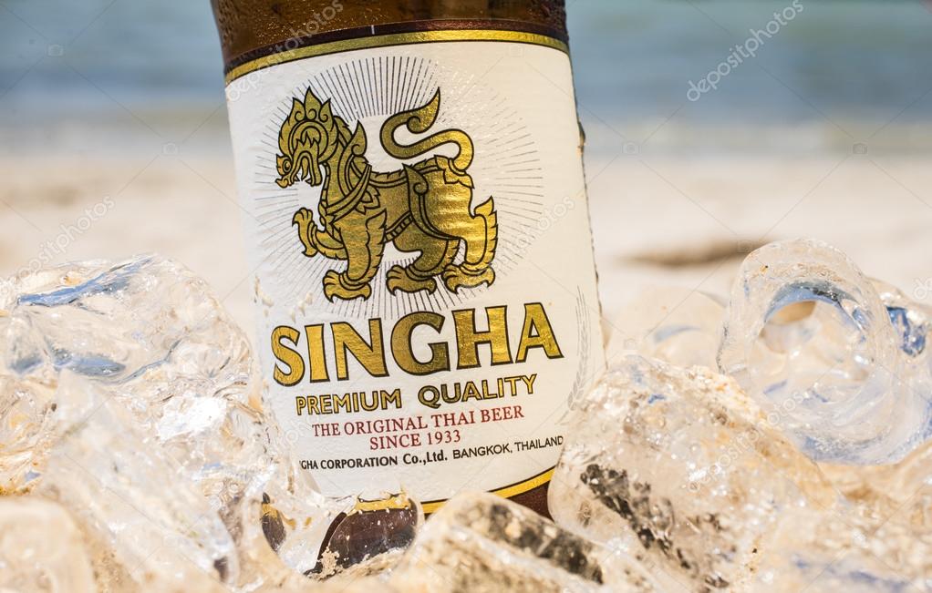 PHI PHI ISLAND,THAILAND - FEBRUARY 27,2015: bottle of Singha beer on the beach  .Produced by Boon Rawd Brewery it is the only brewery permitted to display the royal Garuda on the bottleneck.