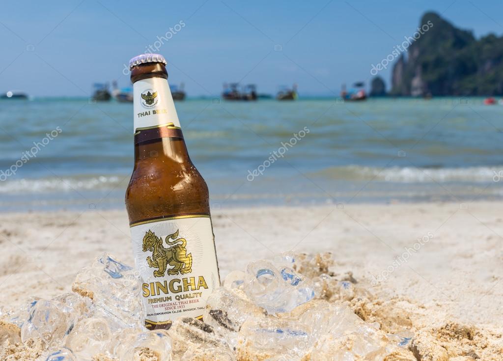 PHI PHI ISLAND,THAILAND - FEBRUARY 27,2015: bottle of Singha beer on the beach  .Produced by Boon Rawd Brewery it is the only brewery permitted to display the royal Garuda on the bottleneck.