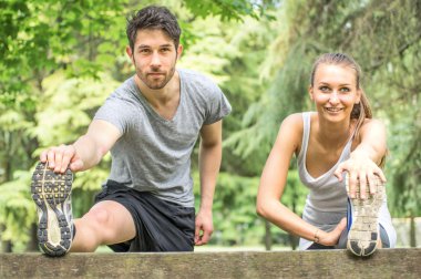 Sporty couple stretching legs outdoors