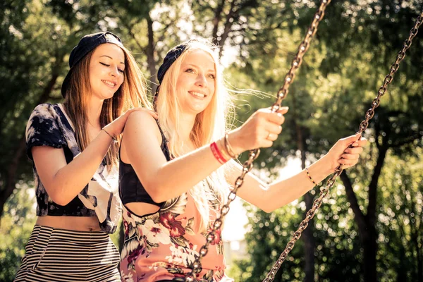 Vrouwen spelen op een schommel bij zonsondergang — Stockfoto