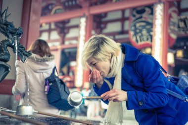 Woman drinking water from asakusa fountain clipart
