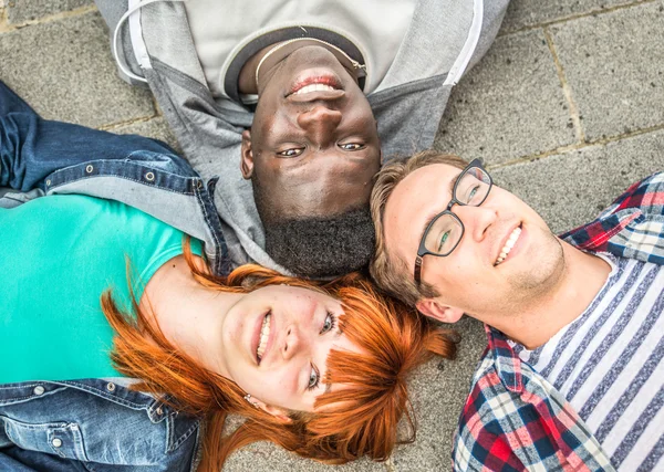 Tři přátelé smíšené rasy, ležící na zemi — Stock fotografie
