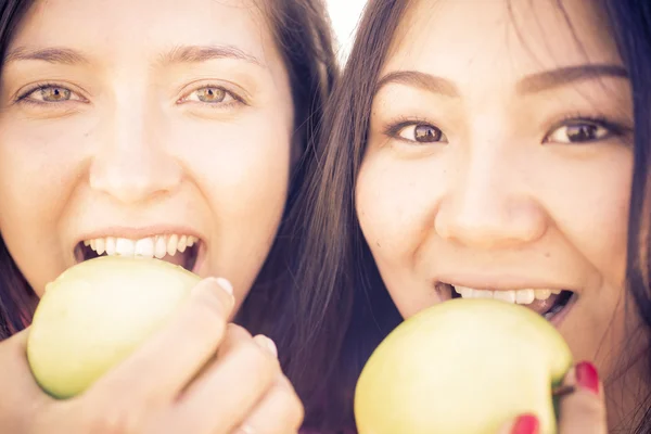 Par de chicas mordiendo manzanas verdes —  Fotos de Stock