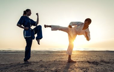 couple training in martial arts on the beach  clipart