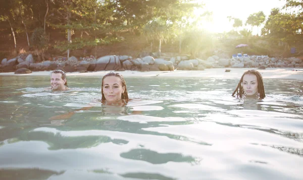 Trois amis nageant ensemble au coucher du soleil — Photo