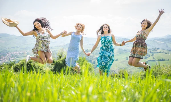 Cuatro chicas saltando juntas en la naturaleza — Foto de Stock