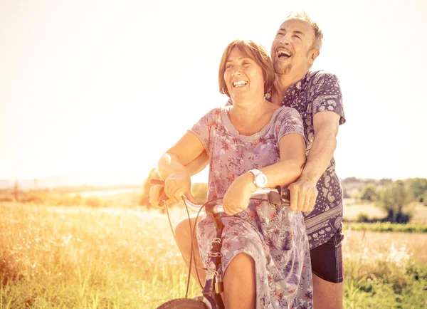 Pareja de mediana edad que va a dar un paseo con la bicicleta en el campo —  Fotos de Stock