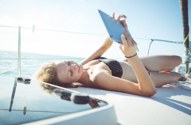 kadın teknede seyir ederken onun tablet üzerine bir kitap okuma