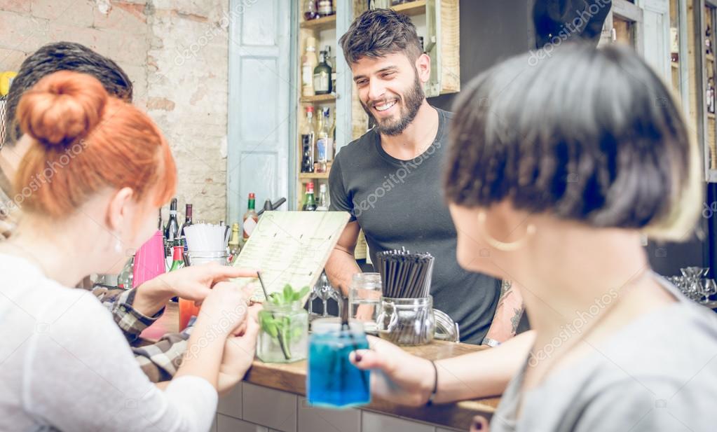 group of friends choosing cocktail from the menu in a bar