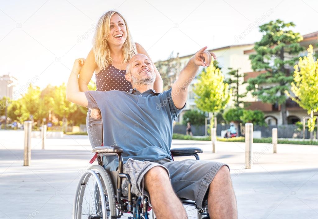 couple in love in the city center. man with desease on a wheelchair and his lovely woman